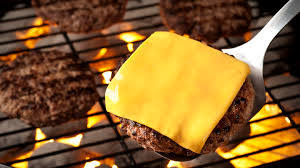 A burger on a spatula with a fresh peice of cheese on top.